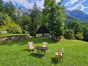 uma mesa e cadeiras em um campo com um celeiro em Hiška Polhec em Bovec