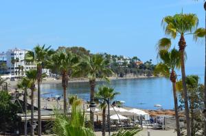 a beach with palm trees and a body of water at Estepona Beach Frontline Deluxe 3BR Condo in Estepona