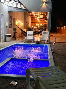 HOTEL & RANCHO Kk في Coxim: حوض استحمام ساخن مع إضاءة أرجوانية في الحديقة الخلفية