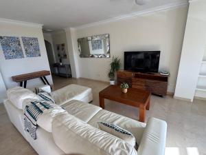 a living room with white furniture and a flat screen tv at Estepona Beach Frontline Deluxe 3BR Condo in Estepona