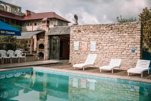 ein Swimmingpool mit zwei Stühlen neben einer Ziegelmauer in der Unterkunft La Badea Mircea in Soroca