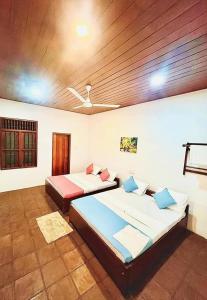 a bedroom with two beds and a wooden ceiling at Himasha Guest in Mirissa