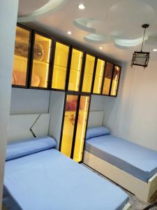 two beds in a small room with yellow cabinets at شقة مميزة بجوار كورنيش النيل اسوان - عائلات فقط in Aswan