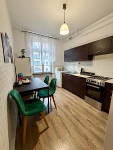 a kitchen with a table and some green chairs at Rynek Ratusz in Wrocław