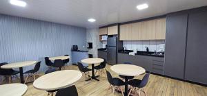 Una habitación con mesas y sillas y una cocina. en POUSADA CITRINO, en Ametista do Sul