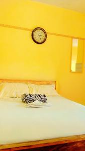 ein Bett mit einer Uhr an einer gelben Wand in der Unterkunft Swahili BNB Homes in Kilifi