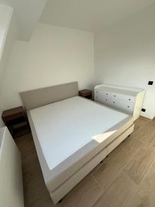 um quarto branco com uma cama e uma cómoda em Luxurious apartment with feet in the sea & city em Ostend