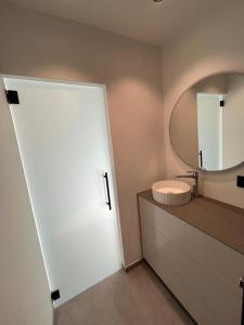 uma casa de banho com uma porta branca e um espelho em Luxurious apartment with feet in the sea & city em Ostend