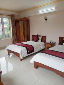 Un dormitorio con dos camas y una ventana. en Khách sạn Thành Loan 2, en Cao Bằng