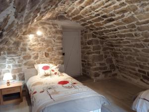 una camera da letto con un letto in un muro di pietra di Gîte L'écrin De Pierres a Les Vignes
