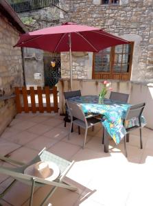 un tavolo da patio con ombrellone e sedie rossi di Gîte L'écrin De Pierres a Les Vignes