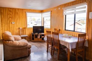 ein Esszimmer mit Tisch und Stühlen und einem Fernseher in der Unterkunft Cabañas Sierra Dorotea in Puerto Natales