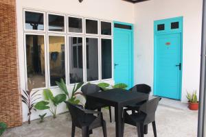 a patio with a black table and chairs and blue doors at Filladhoo inn in Filadu