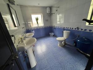 Indigo Orchid Homestay - A spacious, serene villa with terrace and farm view في Saligao: حمام ابيض و ازرق و مغسلتين و مرحاض +14 صورة