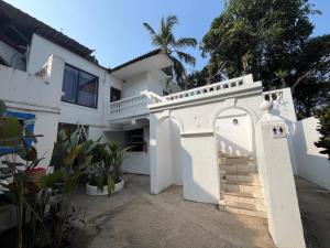 Indigo Orchid Homestay - A spacious, serene villa with terrace and farm view في Saligao: بيت ابيض فيه بوابة والنخيل