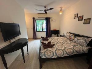 Indigo Orchid Homestay - A spacious, serene villa with terrace and farm view في Saligao: غرفة نوم بسرير مع بيانو وتلفزيون