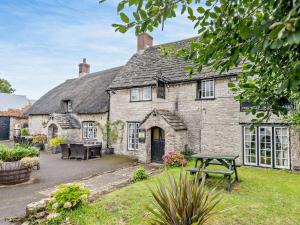 4 Bed in Wareham oc-dc125 في كورف كاسل: منزل حجري قديم مع طاولة نزهة في الفناء