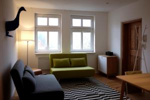 a living room with a green couch and two windows at Blaue Gans in Oderberg