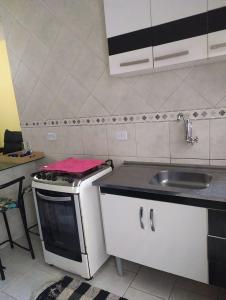 a small kitchen with a sink and a stove at Casa Temporada Caraguatatuba in Caraguatatuba