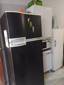 a black refrigerator with a sticker on it in a kitchen at Casa Temporada Caraguatatuba in Caraguatatuba