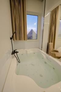 a bath tub in a room with a window at First Site OF Pyramids View & Jacuzzi in Cairo