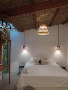 a bedroom with a white bed and a light fixture at Casa mangarito - suítes in Ubatuba