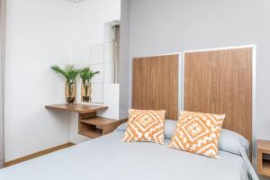 a bedroom with a white bed with two pillows at BaruHaus Centro Valencia de don Juan in Valencia de Don Juan +8 photos