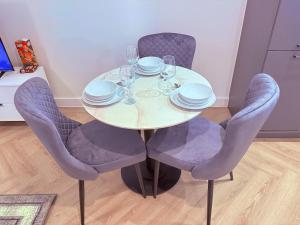 Best Area Stylish1Bed, Games, Relax, Parking في برمنغهام: طاولة مع الكراسي والأطباق وكؤوس النبيذ +صورتان