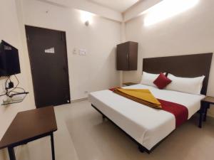 a bedroom with a large bed and a desk and a television at Super Hotel O Red Moon Residency in Chennai