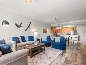 a living room with blue furniture and a kitchen at Sanctuary at Redfish 1106 by Newman-Dailey in Blue Mountain Beach