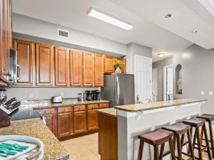 a kitchen with wooden cabinets and a stainless steel refrigerator at Sanctuary at Redfish 1106 by Newman-Dailey in Blue Mountain Beach +59 photos
