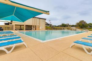 a swimming pool with two lounge chairs and an umbrella at Modern Point Venture Vacation Rental w/ Deck! in Point Venture
