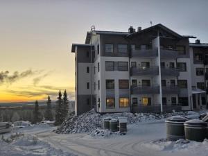 a large building in the snow with barrels in front of it at Ylläs Chalet 9212 in Ylläsjärvi