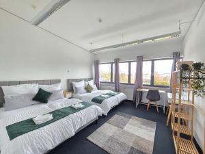 a bedroom with two beds and a desk and window at Große Wohnung mit Balkon nahe München in Ismaning
