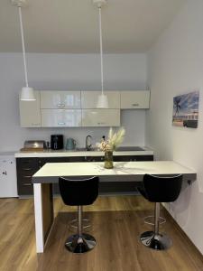 a kitchen with a white counter and two bar stools at CenterPoint Apartment in Karlovy Vary
