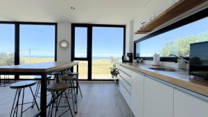 a kitchen with a counter and a table and some windows at Casa Altamar - Casa Con Vista Al Mar en Playa Cruz del Sur, Chapadmalal Para 6 PAX Con Parrilla y Cochera - Hola Sur in Chapadmalal