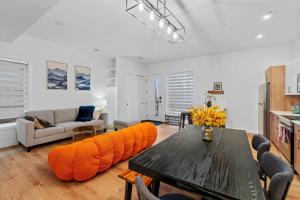 a living room with a table and orange cushioned chairs at Luxurious Large 3 Bedroom Loft Saskatchewan Drive in Edmonton