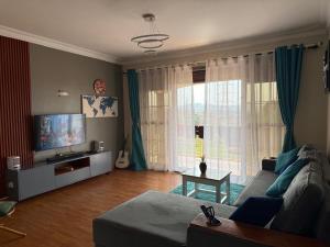 a living room with a couch and a large window at Ariette Homes in Buwate