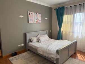 a bedroom with a bed with a blue curtain and a window at Ariette Homes in Buwate