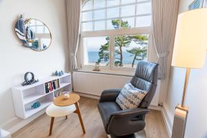 ein Wohnzimmer mit einem Stuhl, einem Tisch und einem Fenster in der Unterkunft Villa Carmen in Bansin