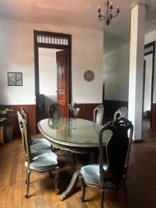 a dining room with a glass table and chairs at Casa-Hostal La Casona in Roldanillo