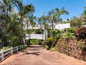 a bridge over a brick road with trees and a fence at Skiathos at Beachfront Apartments in Shakas Rock in Ballito