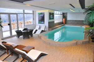 a pool in a hotel room with chairs and a table at Apartman Foka Spa in Brzeće