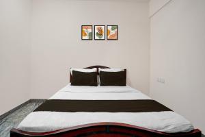 a bedroom with a large bed with black pillows at Hotel O Bhuvika Residency in Jālahalli