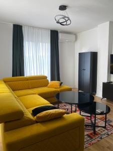 a living room with a yellow couch and a table at Villa Sunny Alley - Sunčani Sokak in Sarajevo