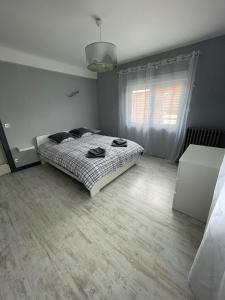 Una habitación blanca con una cama y una ventana en La petite maison des bleuets, en Romorantin-Lanthenay