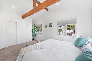 ein weißes Schlafzimmer mit einem großen Bett und einem Fenster in der Unterkunft Laguna Beach Coastal Cottage in Laguna Beach