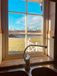 a kitchen sink with a window looking out at a field at Aspudden en pärla i Sörmland in Vingåker