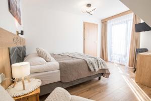a white bedroom with a bed and a chair at Apartamenty i Pokoje Gościnne U Trebuni in Murzasichle +60 photos