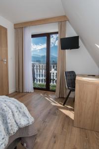 een slaapkamer met een bed en uitzicht op een balkon bij Apartamenty i Pokoje Gościnne U Trebuni in Murzasichle